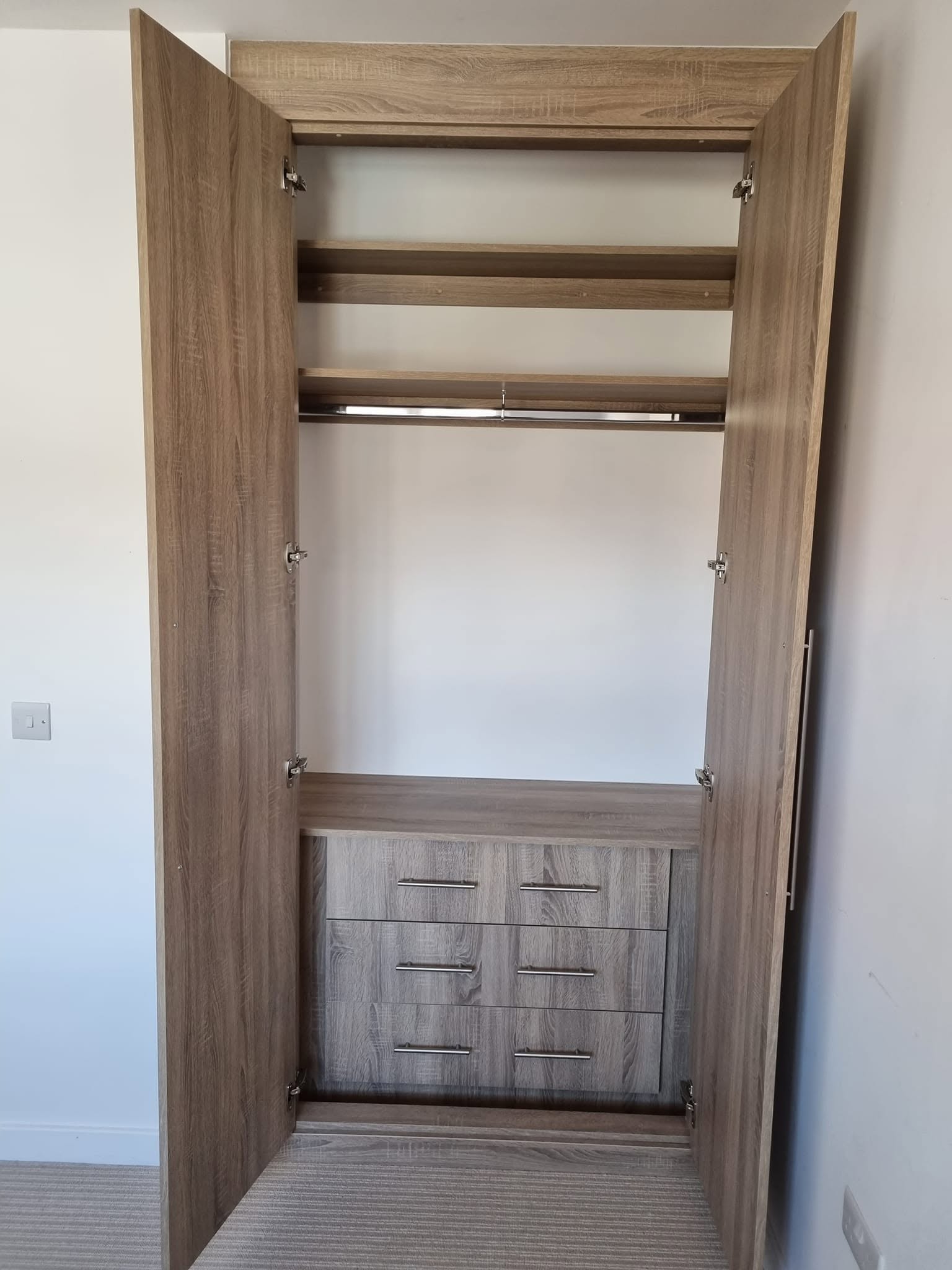 Bespoke fitted wardrobe open, showing oak-finish shelving, hanging rail and a run of drawers, Edinburgh