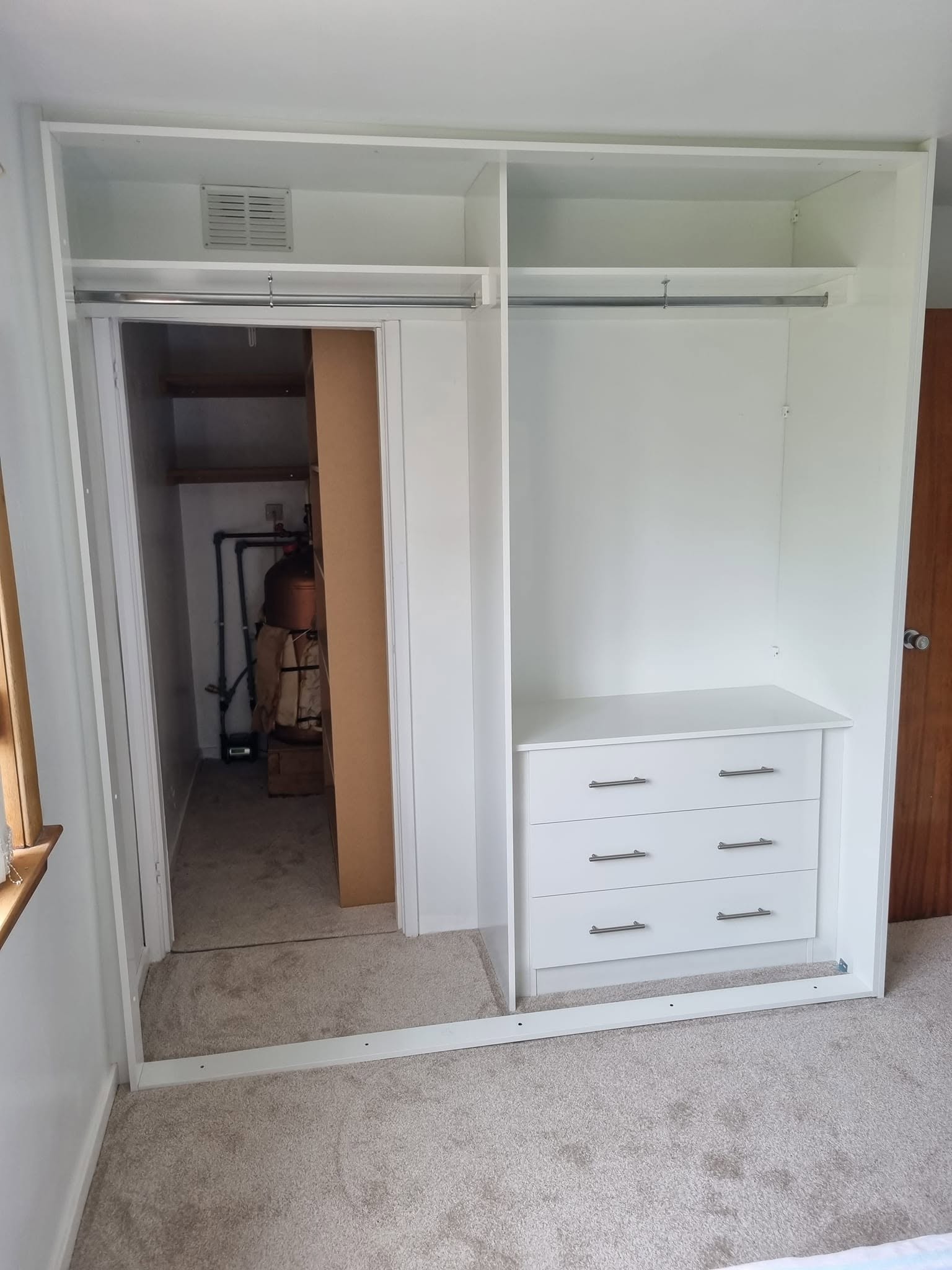 Bespoke walk-in wardrobe frame with hanging rails and drawers beside a storage doorway, Edinburgh